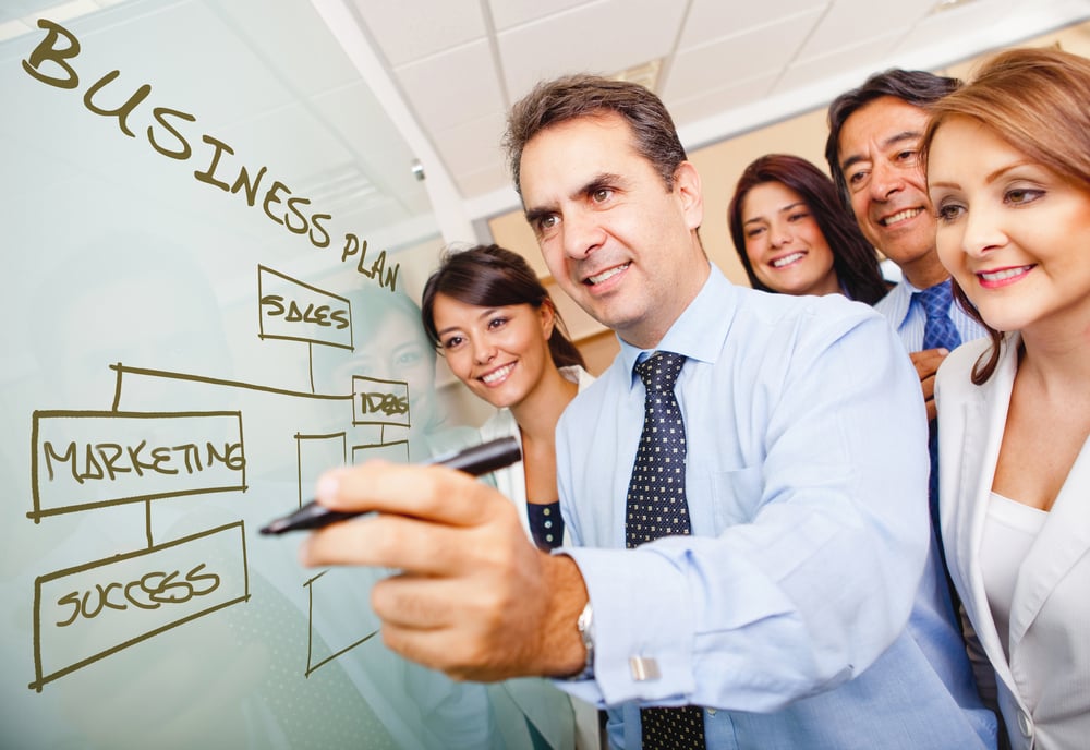 Corporate group drawing a business plan on the board